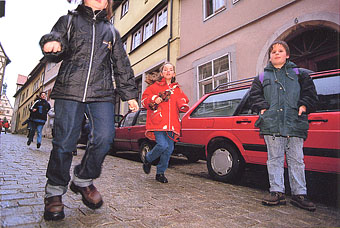 Children skipping down from the school, girl's umbrella is also smart. Rothenburg
