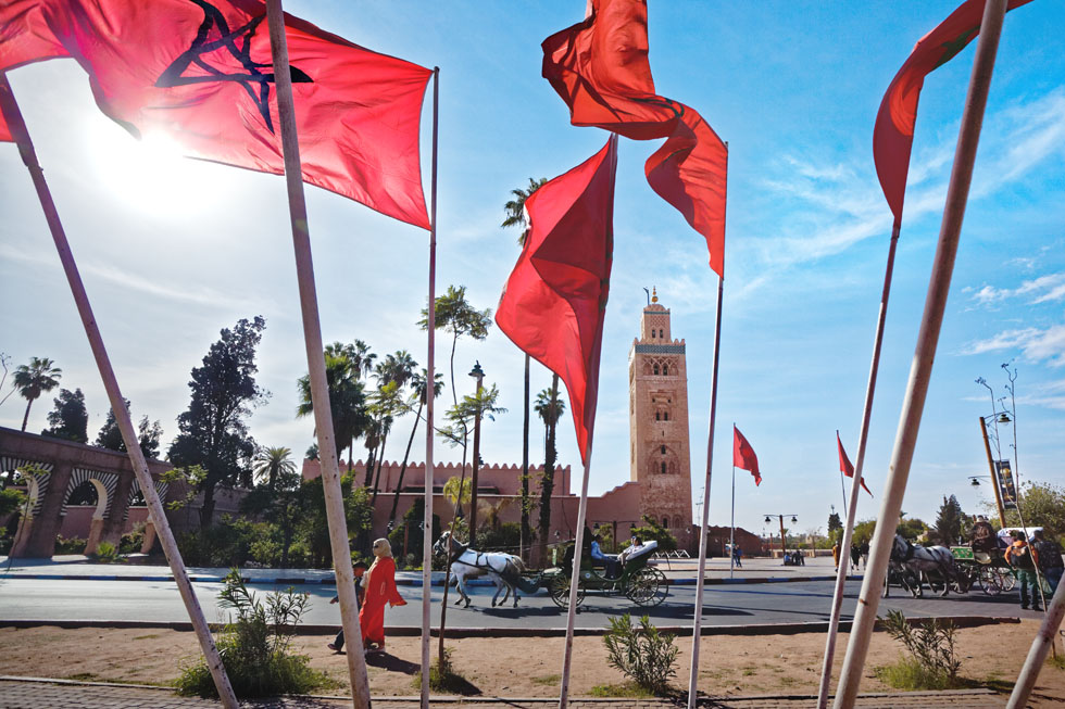 マラケシュの象徴クトゥビーヤ・モスクをバックに赤いモロッコ国旗がはためく